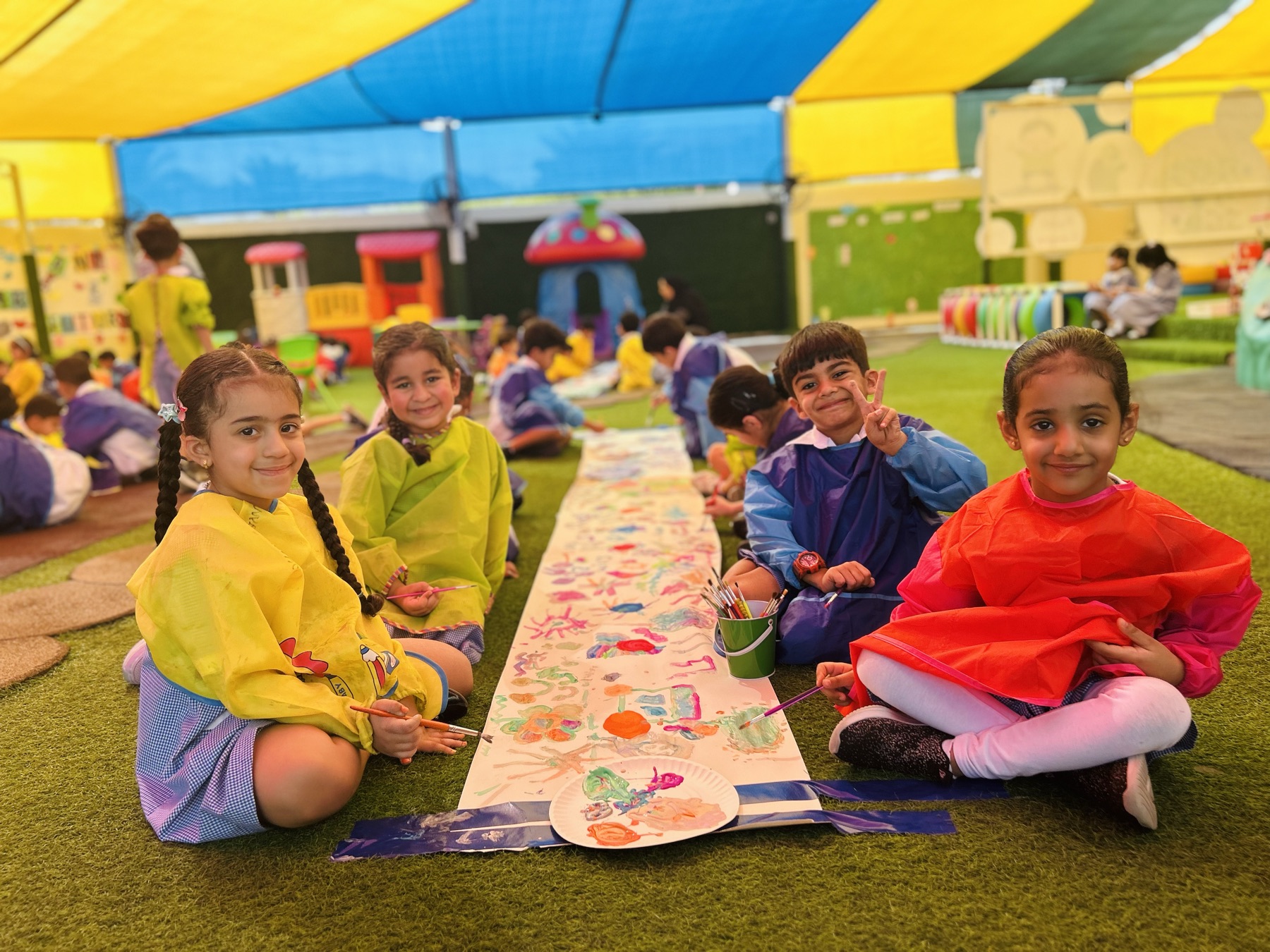 Little Learners children painting a collaborative mural together during an outdoor art activity